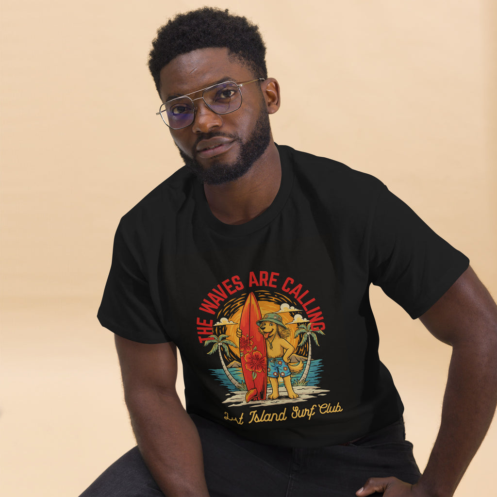 Man in black T-shirt with vibrant island surfing graphic, sitting on stool, looking to the side, casual streetwear look