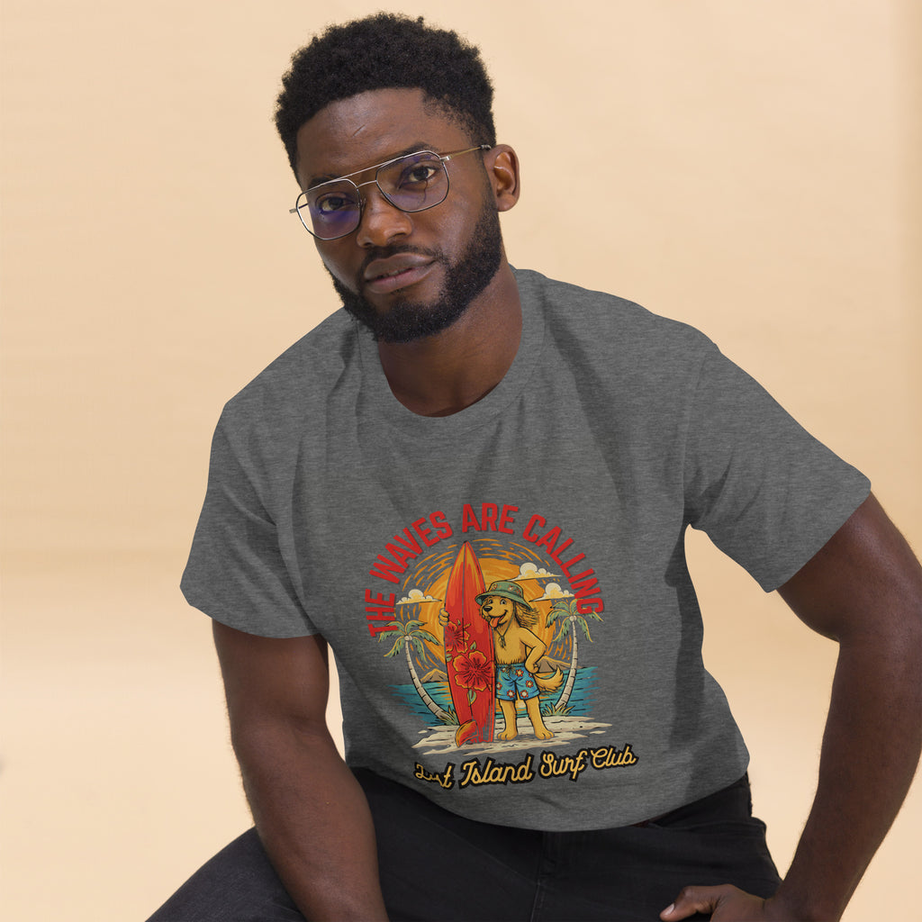 Man wearing dark gray T-shirt with colorful tropical surfing scene, posing against beige background, casual fashion style