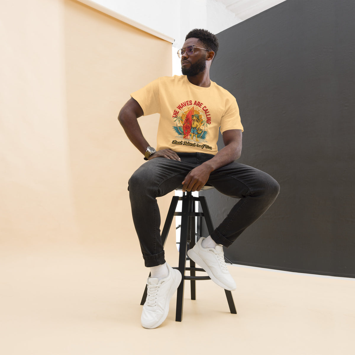 Close-up of man wearing yellow cotton T-shirt with tropical surfing design, relaxed pose, and neutral background